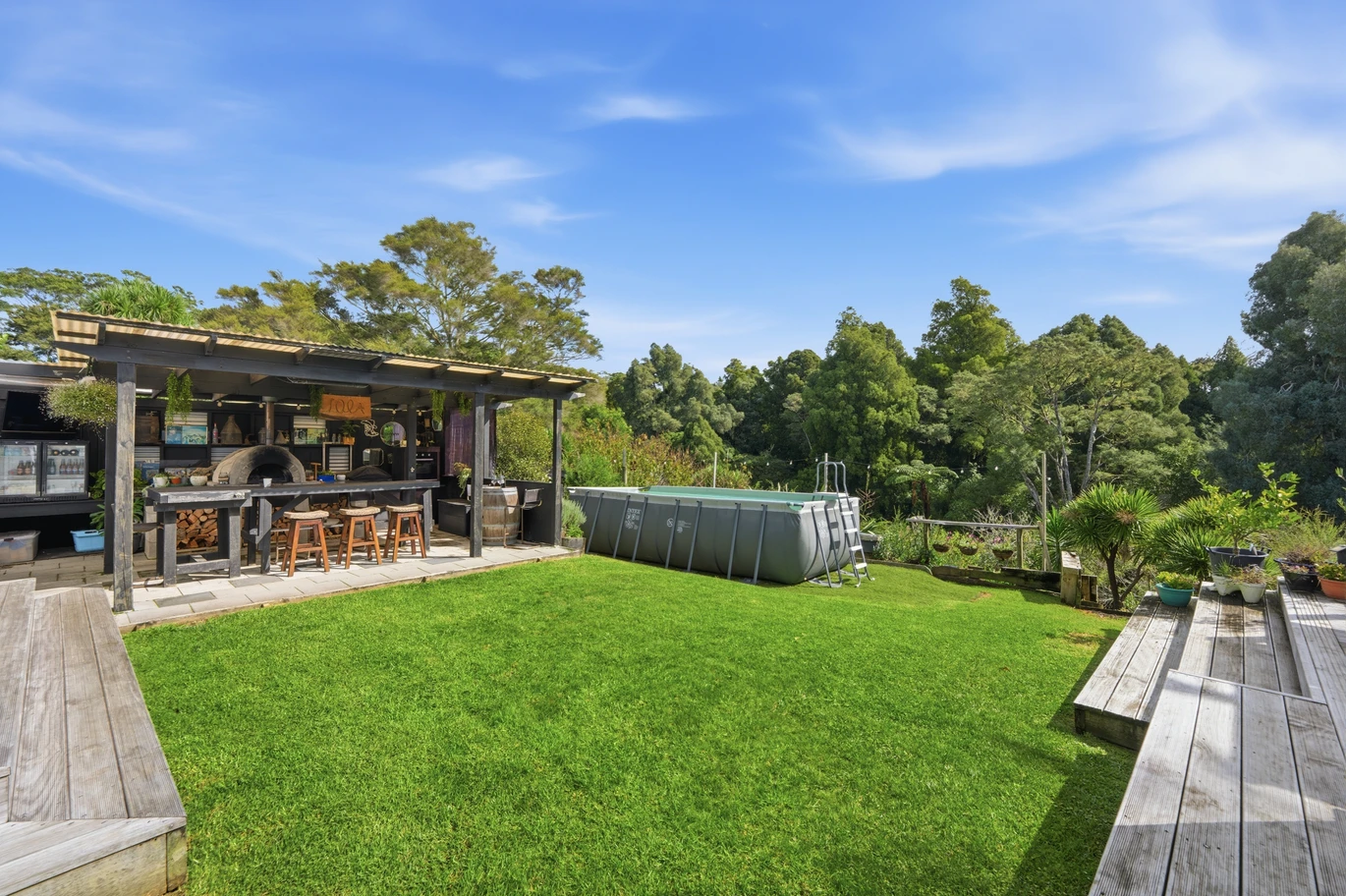 909m2 section, 158m2 4 beds 2 baths main houe PLUS a separate wing/sleepout with a 5th bedroom, bathroom, and covered deck, a massive covered patio with a professional-grade wood-fired pizza oven and a fully equipped outdoor bar area, a large carport, close to reserves, local shops, schools, 23 Tabitha Crescent Henderson, Auckland