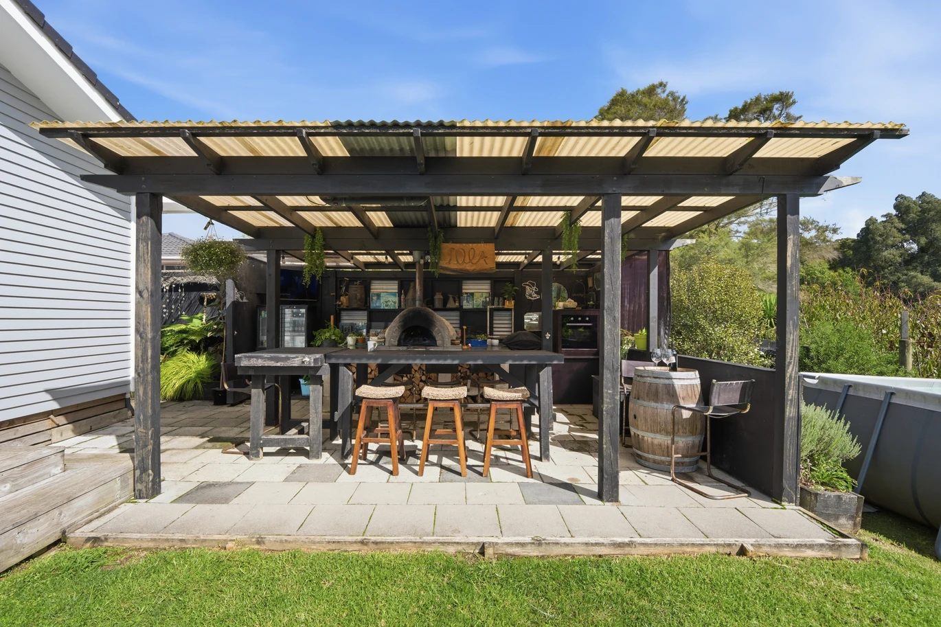 909m2 section, 158m2 4 beds 2 baths main houe PLUS a separate wing/sleepout with a 5th bedroom, bathroom, and covered deck, a massive covered patio with a professional-grade wood-fired pizza oven and a fully equipped outdoor bar area, a large carport, close to reserves, local shops, schools, 23 Tabitha Crescent Henderson, Auckland