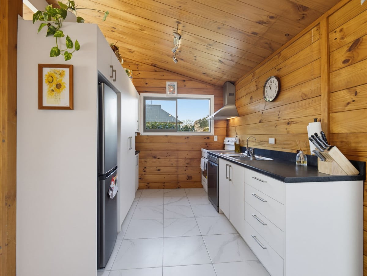 1088m2 section, 3 beds 1 bath house with carport, wooden walls and ceilings wrap around the interconnected lounge, dining area and kitchen. and Outside, the multi-level timber deck, 37A Youngs Road, Papakura, Auckland