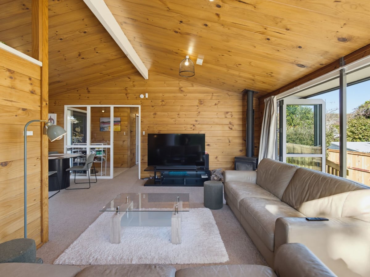 1088m2 section, 3 beds 1 bath house with carport, wooden walls and ceilings wrap around the interconnected lounge, dining area and kitchen. and Outside, the multi-level timber deck, 37A Youngs Road, Papakura, Auckland